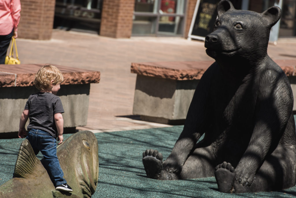 little-boy-plays-on statues-in-old-town-fort-collins