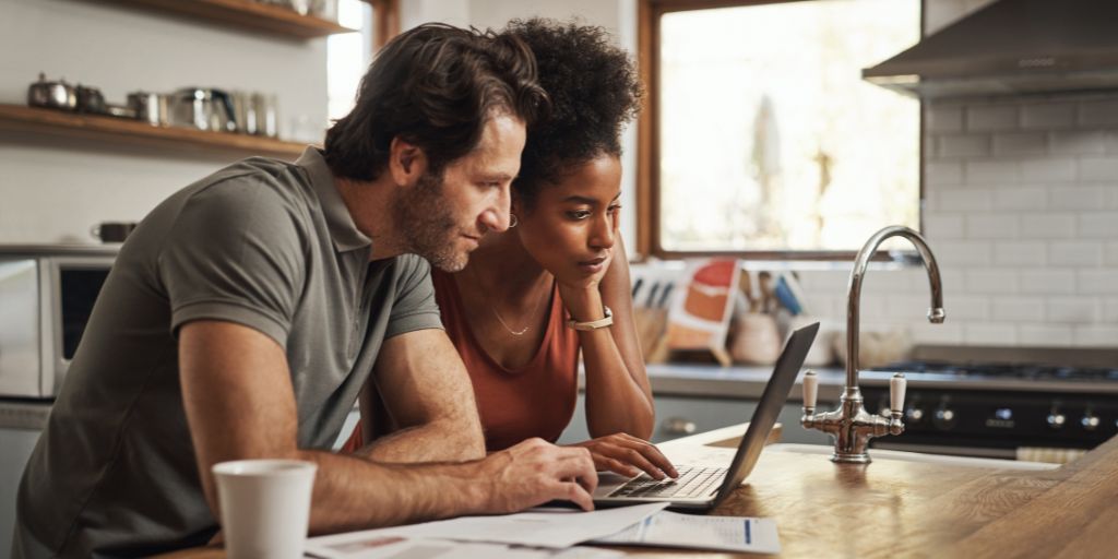 Um casal analisa suas finanças em seu laptop doméstico