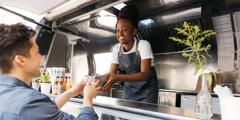 Woman with a business HELOC handing a customer takeout from her food truck